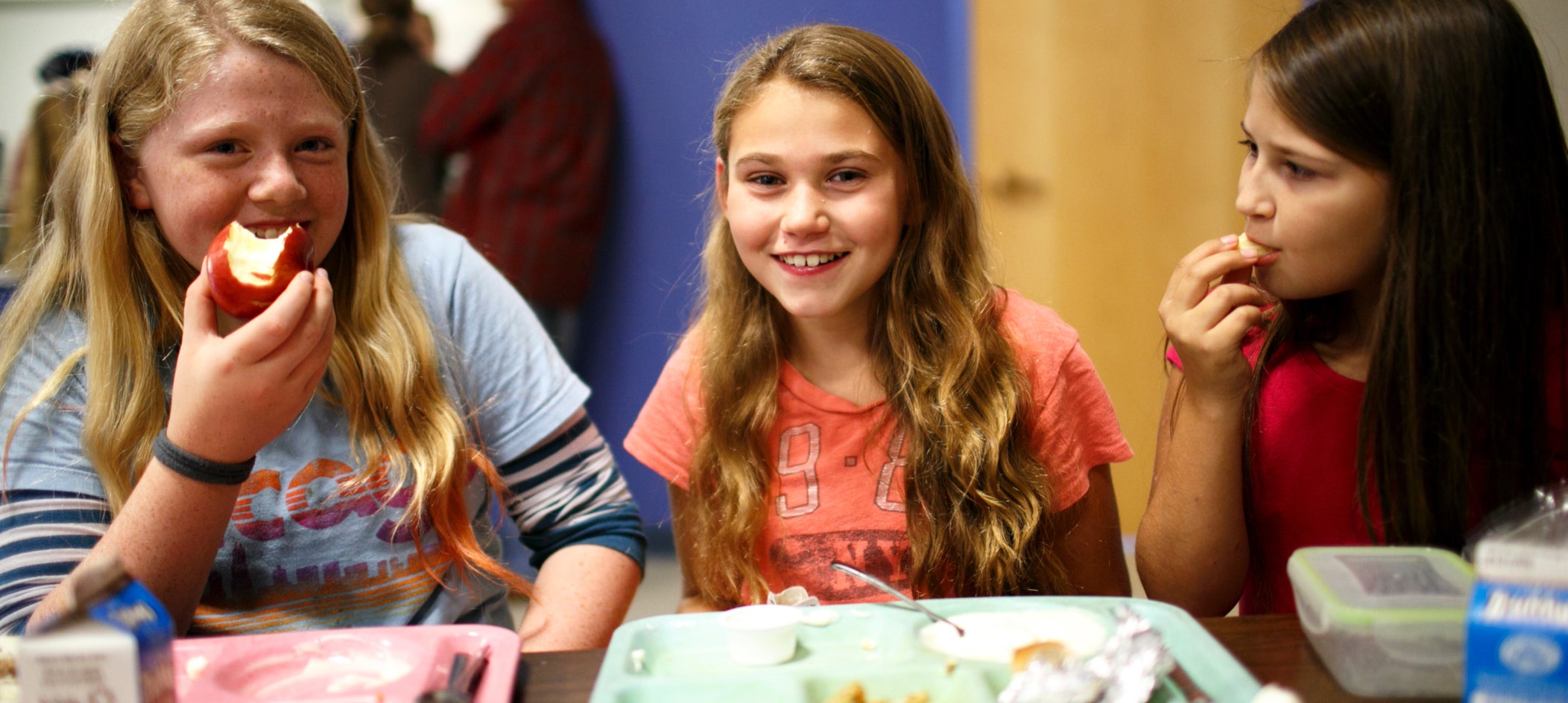 Kids laughing while eating together in a cafeteria 